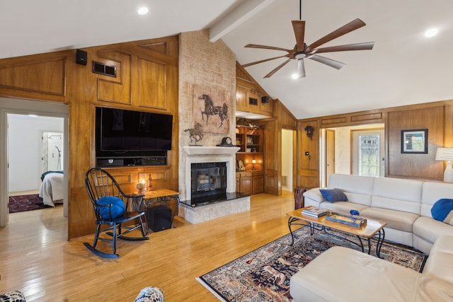 living area featuring visible vents, a large fireplace, wooden walls, light wood-type flooring, and beamed ceiling