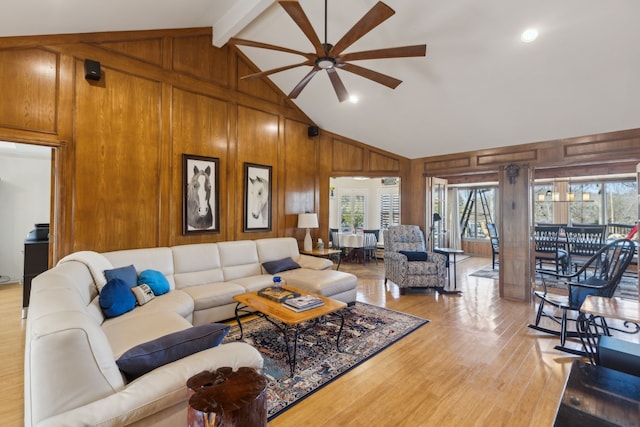 living room with a healthy amount of sunlight, light wood finished floors, wooden walls, and beam ceiling