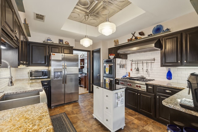 kitchen featuring visible vents, appliances with stainless steel finishes, light stone countertops, a raised ceiling, and custom range hood