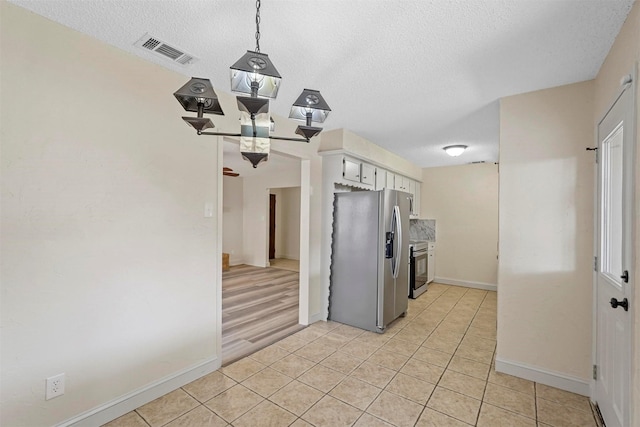 kitchen featuring a textured ceiling, appliances with stainless steel finishes, light tile patterned flooring, and visible vents