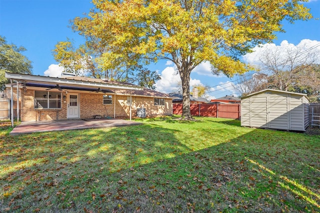 view of yard with an outbuilding, a fenced backyard, a ceiling fan, a storage unit, and a patio area