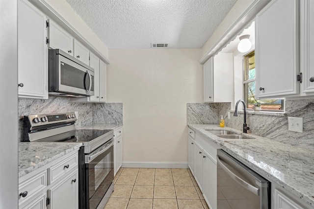 kitchen featuring light tile patterned flooring, a sink, visible vents, white cabinetry, and appliances with stainless steel finishes