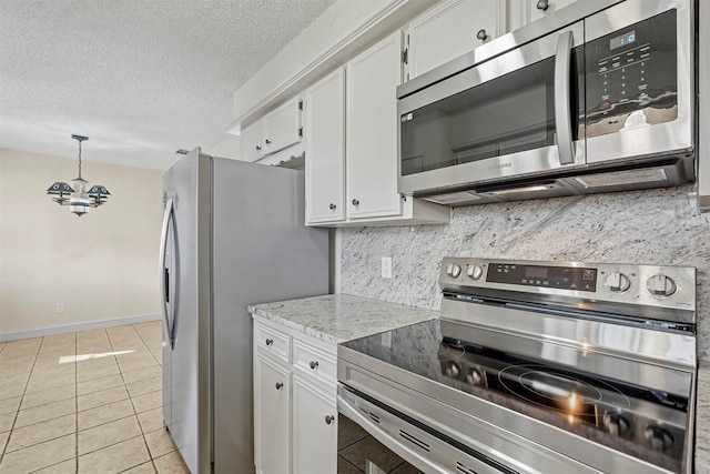 kitchen with a textured ceiling, light tile patterned flooring, stainless steel appliances, white cabinets, and decorative backsplash