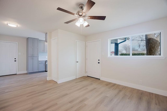 empty room featuring light wood finished floors, a ceiling fan, and baseboards