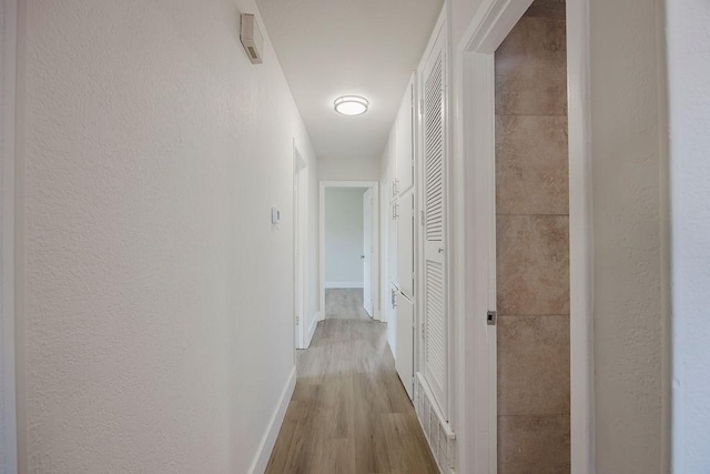 corridor with baseboards and wood finished floors