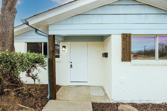 doorway to property featuring brick siding