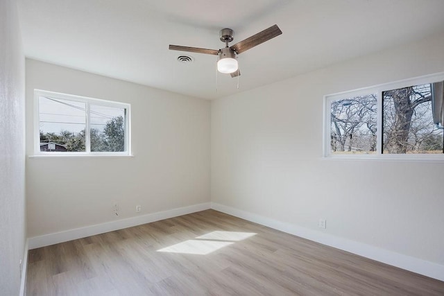 empty room featuring ceiling fan, wood finished floors, visible vents, and baseboards