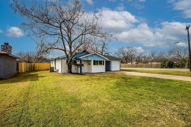 view of yard with a garage, cooling unit, concrete driveway, and fence