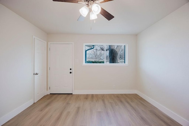 empty room featuring light wood-type flooring, a ceiling fan, and baseboards