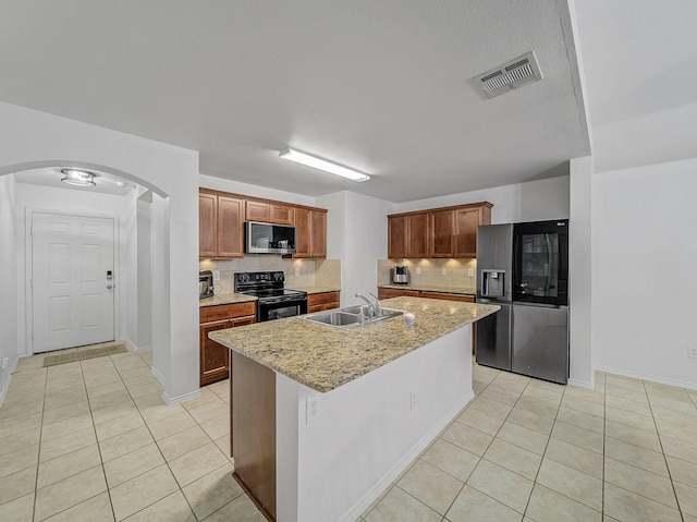 kitchen with light tile patterned floors, arched walkways, visible vents, stainless steel appliances, and a sink