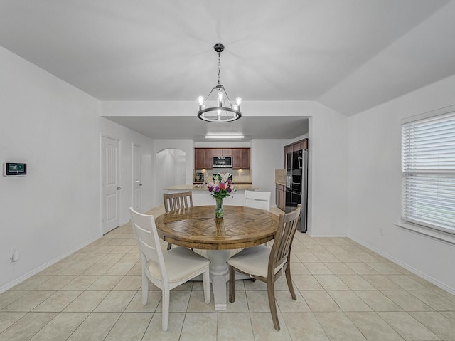 dining area featuring arched walkways, light tile patterned floors, a chandelier, and baseboards