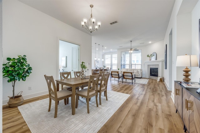 dining area featuring recessed lighting, visible vents, light wood-style floors, a glass covered fireplace, and baseboards