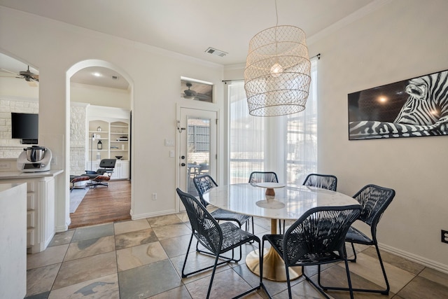 dining area with baseboards, visible vents, arched walkways, crown molding, and ceiling fan with notable chandelier