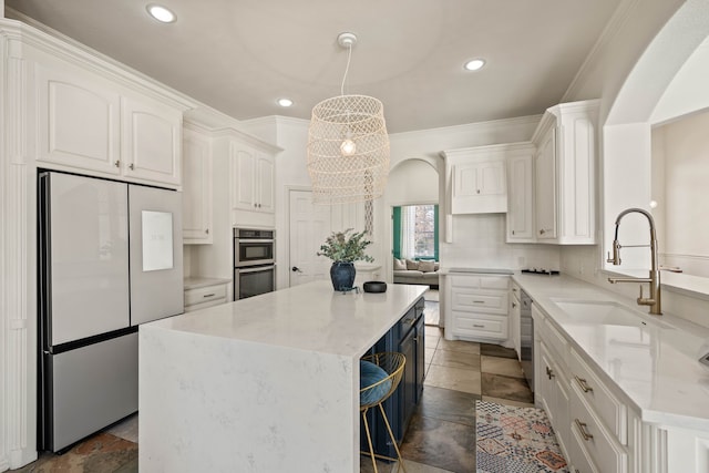 kitchen featuring tasteful backsplash, arched walkways, a kitchen island, stainless steel appliances, and a sink