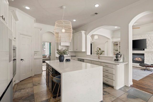 kitchen with visible vents, white cabinets, light countertops, a center island, and crown molding