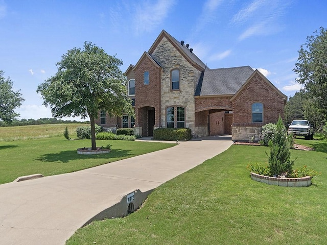 view of front of home with stone siding, brick siding, roof with shingles, and a front yard