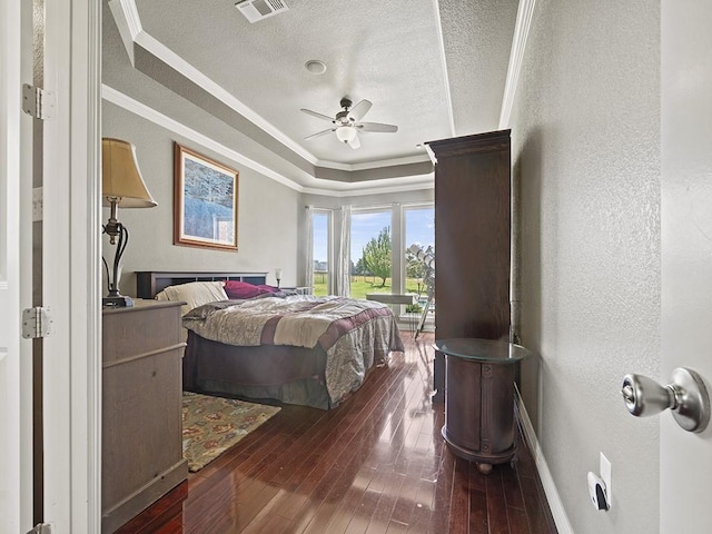 bedroom with a raised ceiling, a textured wall, wood-type flooring, a textured ceiling, and crown molding