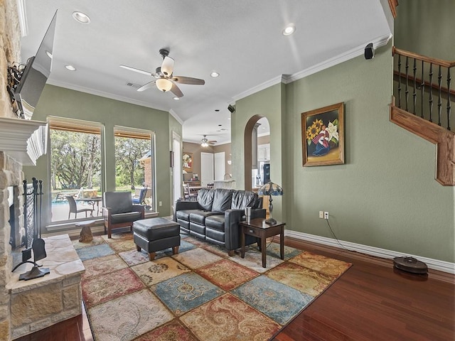 living area with arched walkways, crown molding, a fireplace, wood finished floors, and baseboards