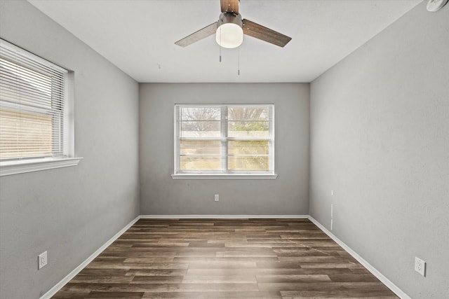 empty room with dark wood-style floors, ceiling fan, and baseboards