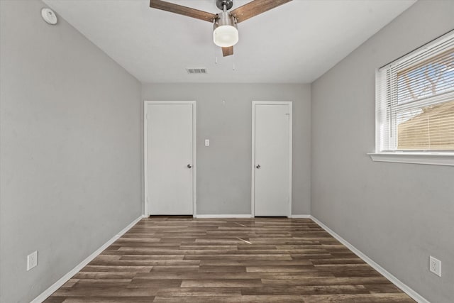 interior space featuring baseboards, visible vents, ceiling fan, and wood finished floors