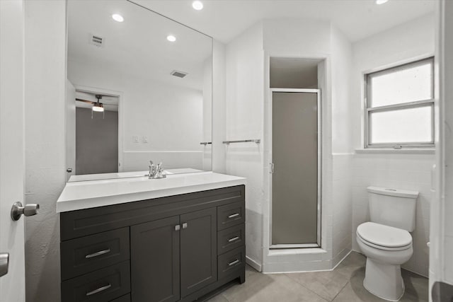 bathroom featuring toilet, a stall shower, vanity, and tile walls