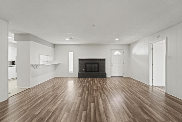 unfurnished living room with a brick fireplace and wood finished floors