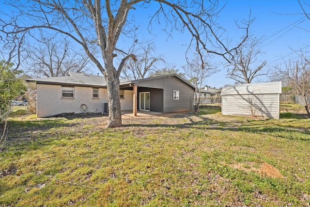 back of house featuring a storage shed, an outdoor structure, fence, a yard, and a patio area