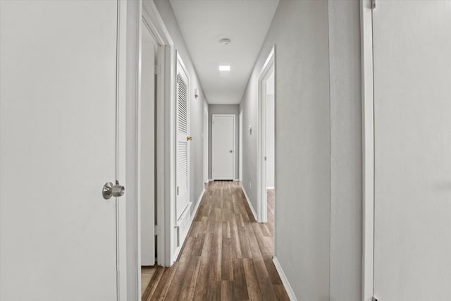 hallway featuring baseboards and dark wood-style flooring