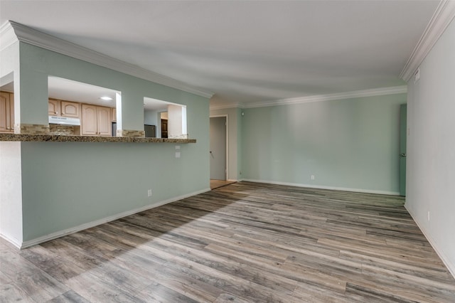 spare room featuring ornamental molding, baseboards, and wood finished floors