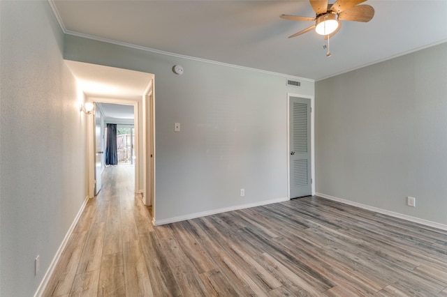 unfurnished room with ornamental molding, wood finished floors, and baseboards