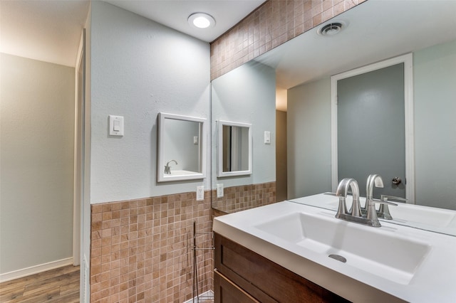 bathroom featuring visible vents, wainscoting, wood finished floors, vanity, and tile walls