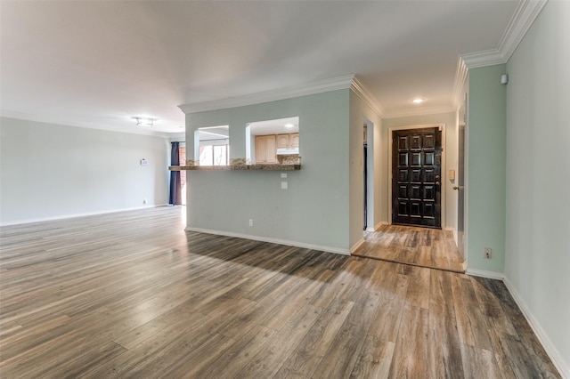 interior space featuring baseboards, wood finished floors, and crown molding