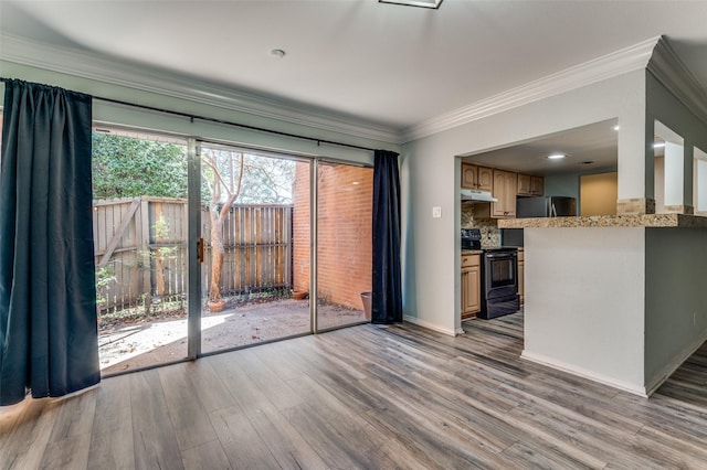 interior space featuring baseboards, wood finished floors, and crown molding