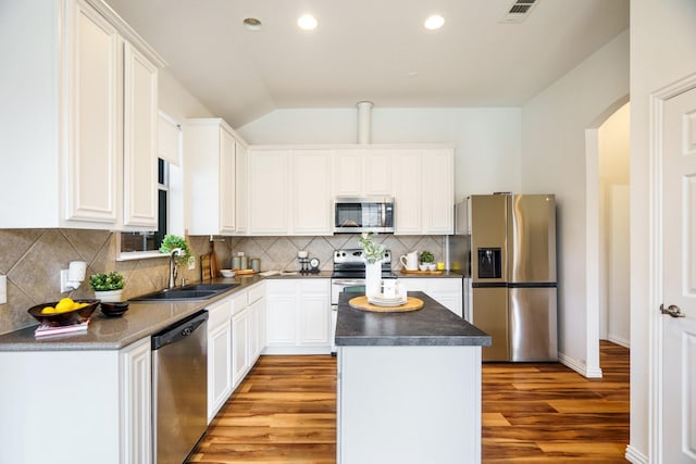 kitchen featuring visible vents, lofted ceiling, a kitchen island, appliances with stainless steel finishes, and a sink