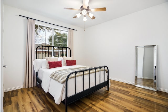 bedroom featuring wood finished floors, a ceiling fan, and baseboards