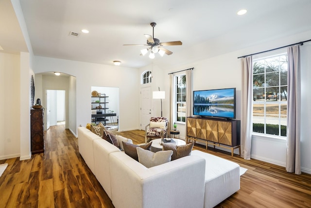 living area with arched walkways, recessed lighting, and wood finished floors