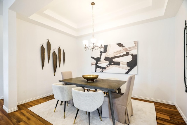 dining room with a raised ceiling, baseboards, and wood finished floors