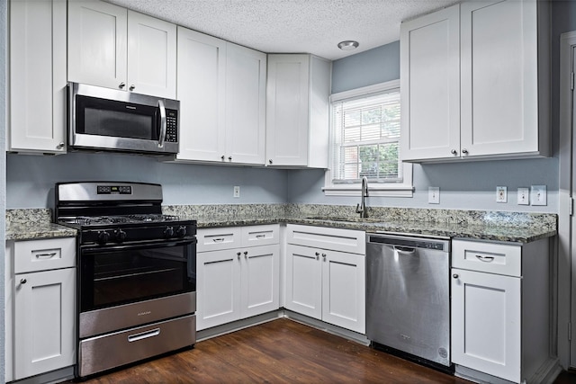 kitchen with dark wood-style floors, stone countertops, appliances with stainless steel finishes, and a sink