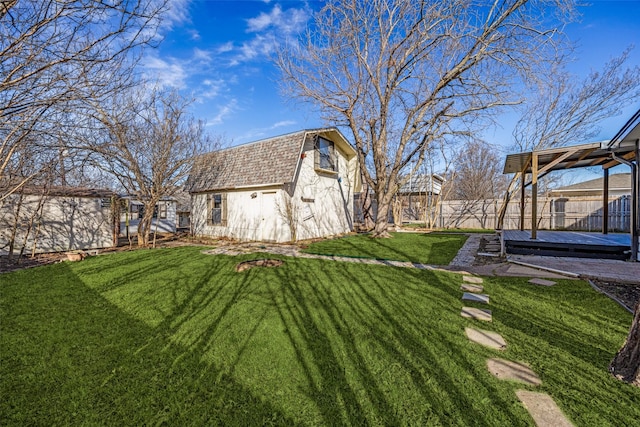 view of yard with a storage shed, a fenced backyard, a wooden deck, and an outdoor structure