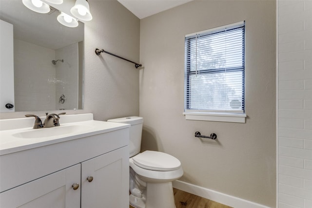 bathroom featuring toilet, vanity, wood finished floors, baseboards, and walk in shower