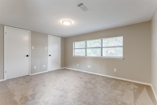 empty room with carpet floors, visible vents, and baseboards