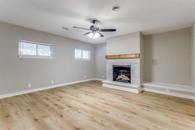 unfurnished living room with light wood-type flooring, a tile fireplace, and visible vents