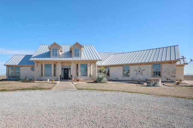 view of front of home featuring metal roof, stone siding, and a standing seam roof