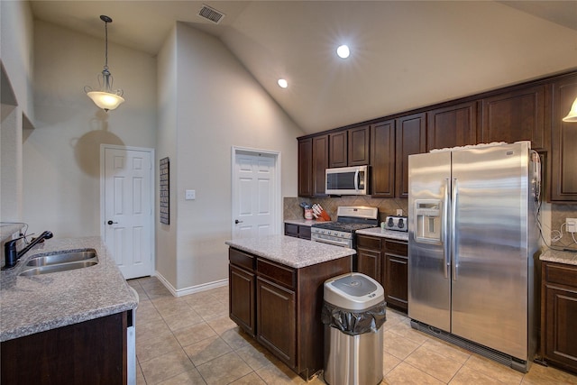 kitchen with a kitchen island, a sink, visible vents, appliances with stainless steel finishes, and backsplash