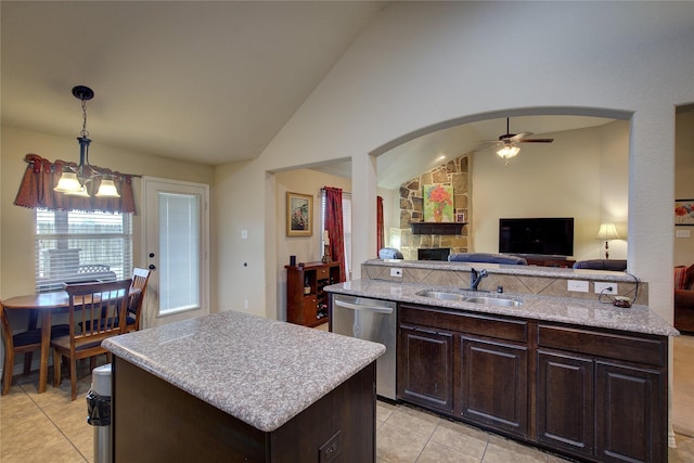 kitchen featuring arched walkways, dark brown cabinetry, a kitchen island, a sink, and stainless steel dishwasher