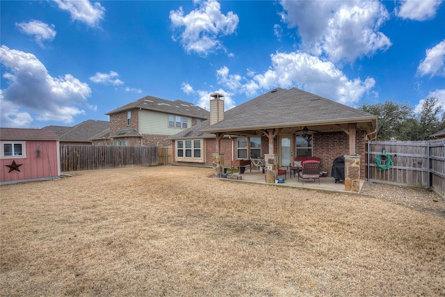 back of house featuring a fenced backyard, a storage unit, an outdoor structure, a patio area, and brick siding