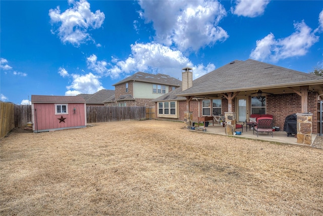 back of house with a fenced backyard, a patio, an outdoor structure, and a shed