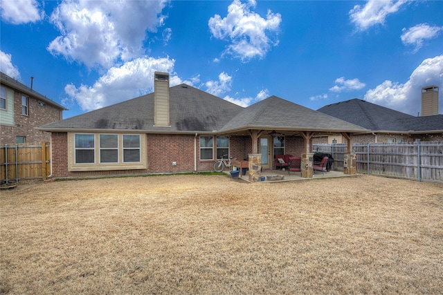 rear view of property with a yard, brick siding, a patio, and a fenced backyard