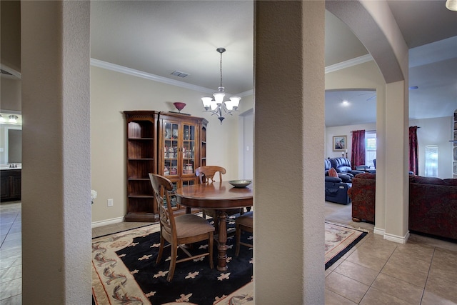 tiled dining area featuring a notable chandelier, baseboards, arched walkways, and crown molding