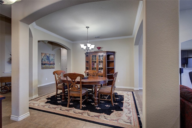 tiled dining room with baseboards, visible vents, arched walkways, ornamental molding, and an inviting chandelier